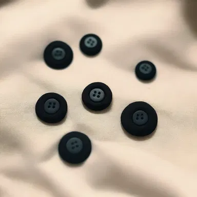 The hack at the fashion house tirelessly sewed buttons onto the designer dresses.