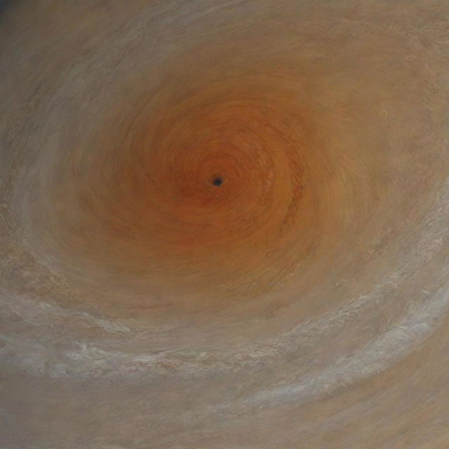 In the midst of Jupiter's Great Red Spot, a swirling storm larger than Earth, with tumultuous crimson clouds against a backdrop of shrouded yellow and orange hues