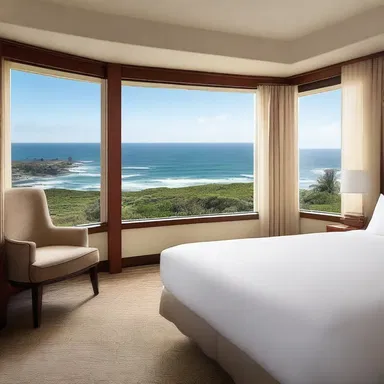 The hotel room has large windows that overlook the beautiful ocean.