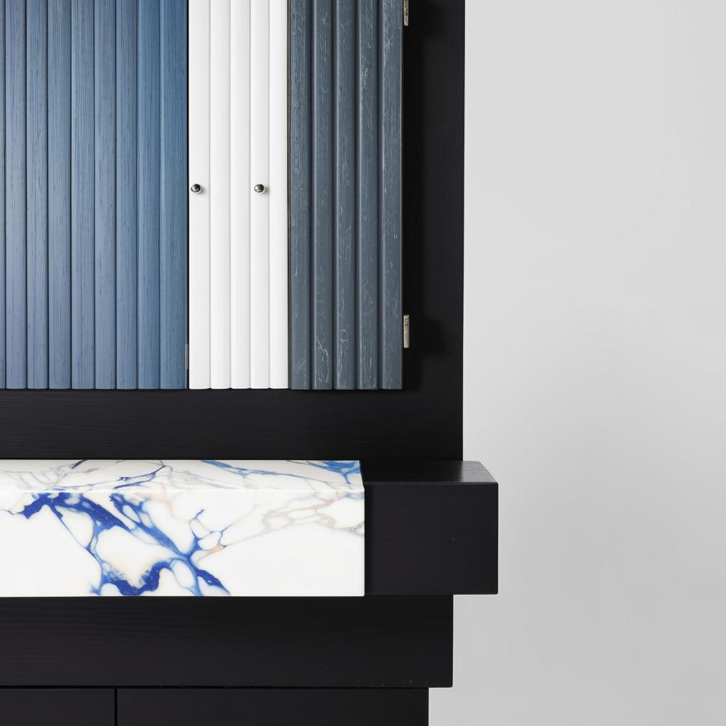 White and blue fluted shutters forming storage unit situated above a black marble side table