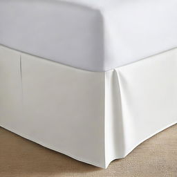 A corner of a bed with a clean bed skirt