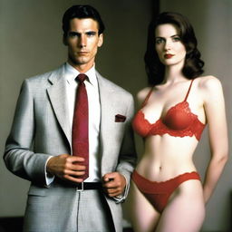 A slender, white man with an effeminate form, wearing a small red lace bra and panties, standing next to his wife who is dressed in a suit and tie