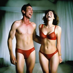 A slender, white man with an effeminate form, wearing a small red lace bra and panties, standing next to his wife who is laughing at him