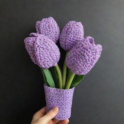 A bouquet of three crocheted tulips in pastel purple color wrapped in a dark purple cover.