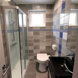 A square shower room with a window, shower cabin, toilet, and black sink