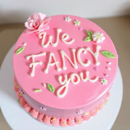 A beautifully decorated pink cake with the inscription 'We FANCY you' written in elegant icing