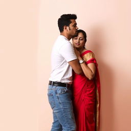 A handsome man wearing a white t-shirt and jeans is giving a kiss on the cheek to a woman who is wearing a red saree