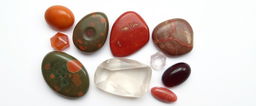 A collection of carnelian, bloodstone, red jasper, clear quartz, and garnet on a white background