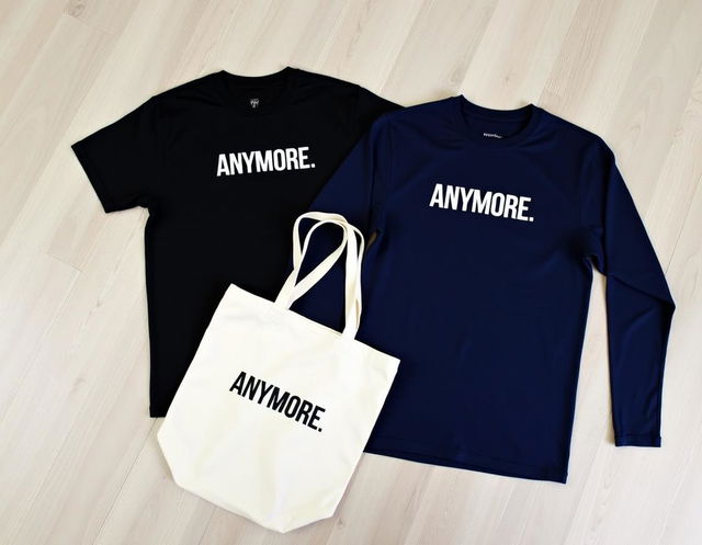 A flat lay image featuring a black t-shirt and a navy blue long-sleeve shirt for both men and women, along with a cream-colored canvas tote bag