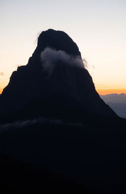 A majestic black mountain rising against a twilight sky, partially shrouded in mist