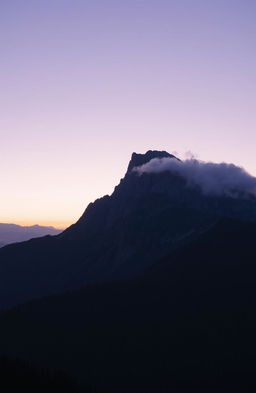 A majestic black mountain rising against a twilight sky, partially shrouded in mist