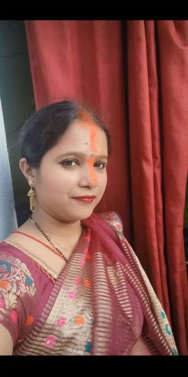 A confident woman in traditional Indian attire, wearing a colorful saree with intricate embroidery