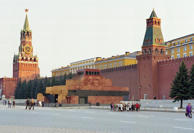 A large queue of people waiting to enter Lenin's Mausoleum in Red Square, with a massive black smoke billowing above the mausoleum