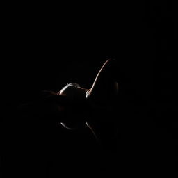 A young, slender woman in a bikini lies on her back sideways in a completely dark space
