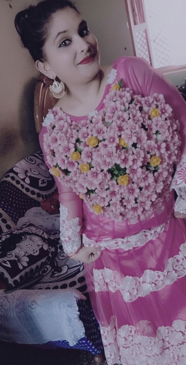 A woman wearing a vibrant pink traditional outfit, smiling and posing indoors