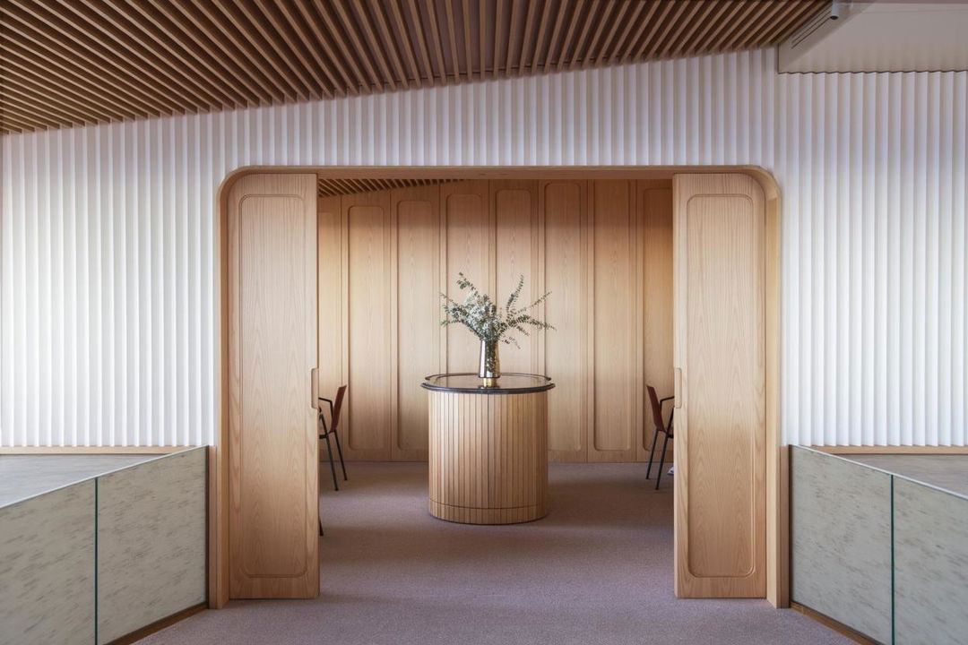 An elegant modern interior featuring a stylish entrance with two curved wooden doors leading into a warm, inviting space