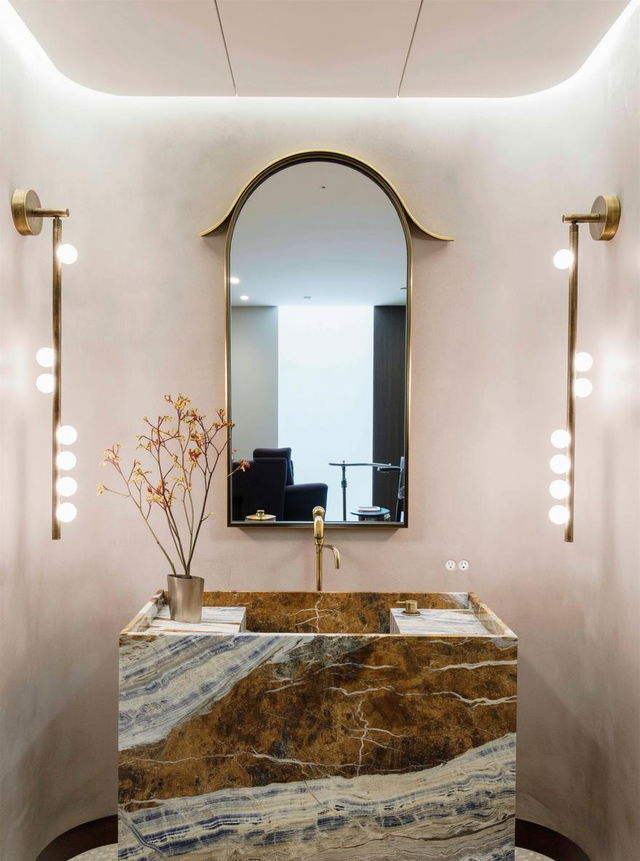 A contemporary bathroom featuring a striking large oval mirror above a luxurious marble sink with intricate brown and gold veining