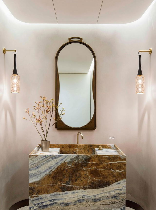 An elegant bathroom showcasing a striking large oval mirror with a sleek gold frame, reflecting the stylish design of the space