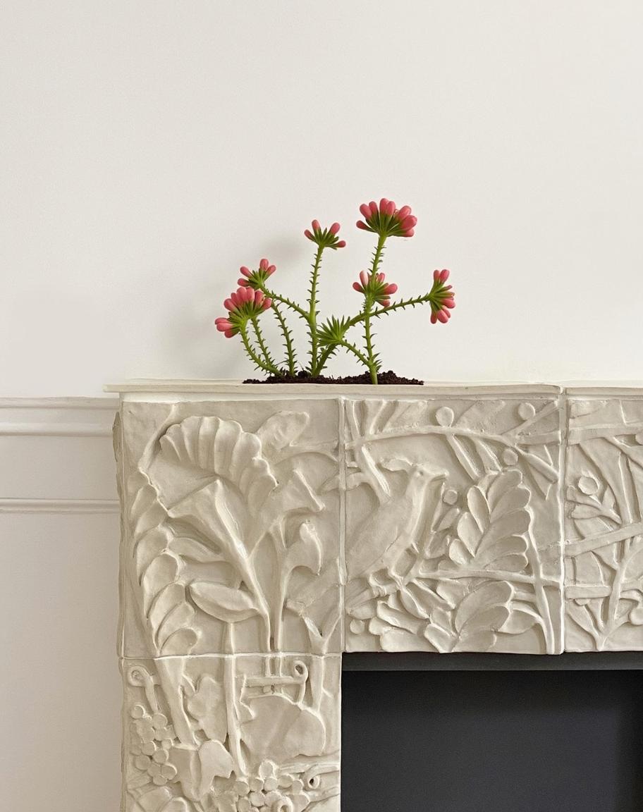 A beautifully designed fireplace mantel adorned with intricate carvings of various plants and foliage, showcasing a naturalistic theme