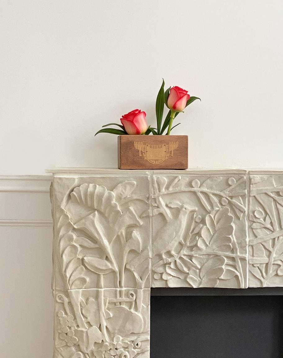 An elegant fireplace mantel intricately carved with floral and foliage designs, showcasing a beautiful display of nature-inspired details