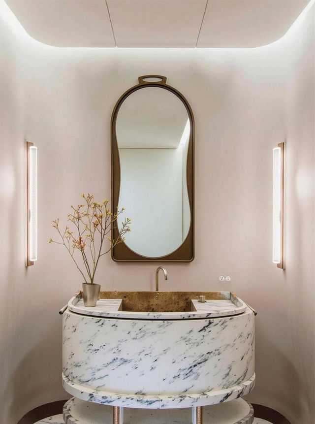 A modern bathroom interior featuring a beautifully designed oval marble sink with a glossy surface and striking dark veining