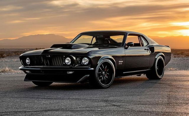 A stunning vintage black muscle car parked on an open road during a breathtaking sunset