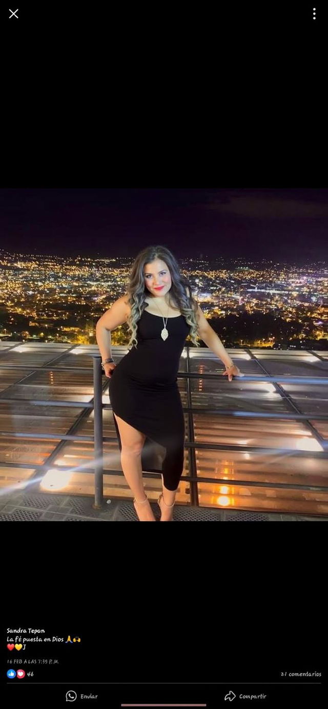 A confident and elegant woman in a stylish black dress standing on a rooftop overlooking a stunning city skyline at night