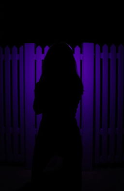 A woman seen from behind, standing in front of three purple fences