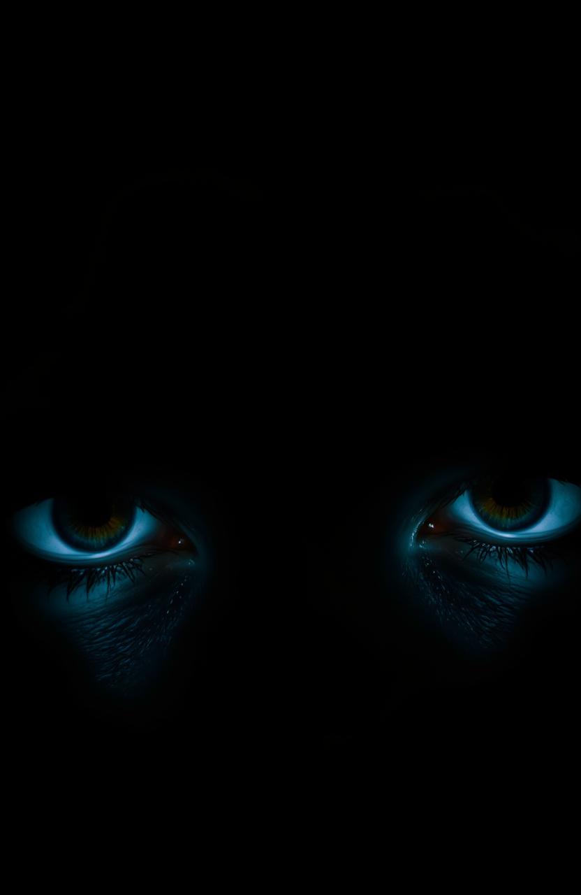 A close-up of a pair of striking eyes illuminated against a dark background, with a captivating gaze that draws the viewer in