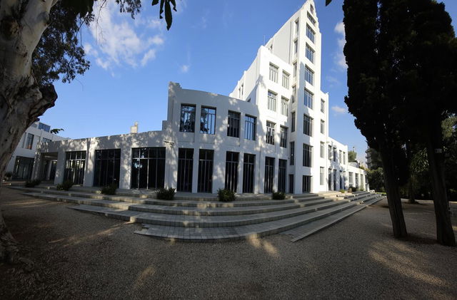 A modern, minimalist architectural building, featuring a combination of large glass windows and smooth white walls