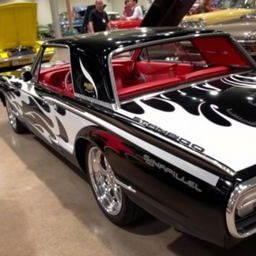 A stunning 1965 Ford Thunderbird show car painted in glossy black with vibrant white flames sweeping across its body