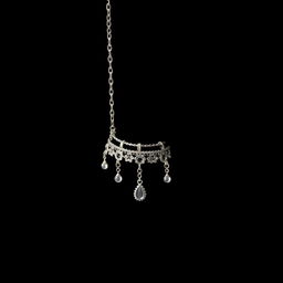 An artistic close-up of a silver anklet gracefully dangling in front of a solid black background