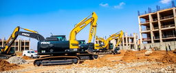 A construction site featuring black and gold excavators with the word 'PROG' displayed prominently