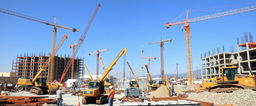 A lively construction site bustling with activity, showcasing various types of heavy machinery including cranes, excavators, and bulldozers working in unison