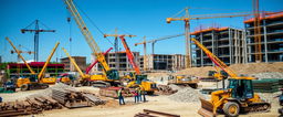 A lively construction site bustling with activity, showcasing various types of heavy machinery including cranes, excavators, and bulldozers working in unison