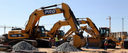 A construction site featuring heavy machinery painted in sleek black and gold colors, prominently displaying the word 'PROG' on the sides of the machinery