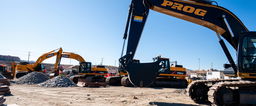 A construction site featuring heavy machinery painted in sleek black and gold colors, prominently displaying the word 'PROG' on the sides of the machinery