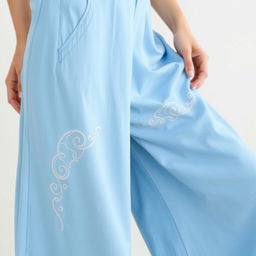 A pair of long pants in a sky blue color, featuring elegant wave embroidery along the seams