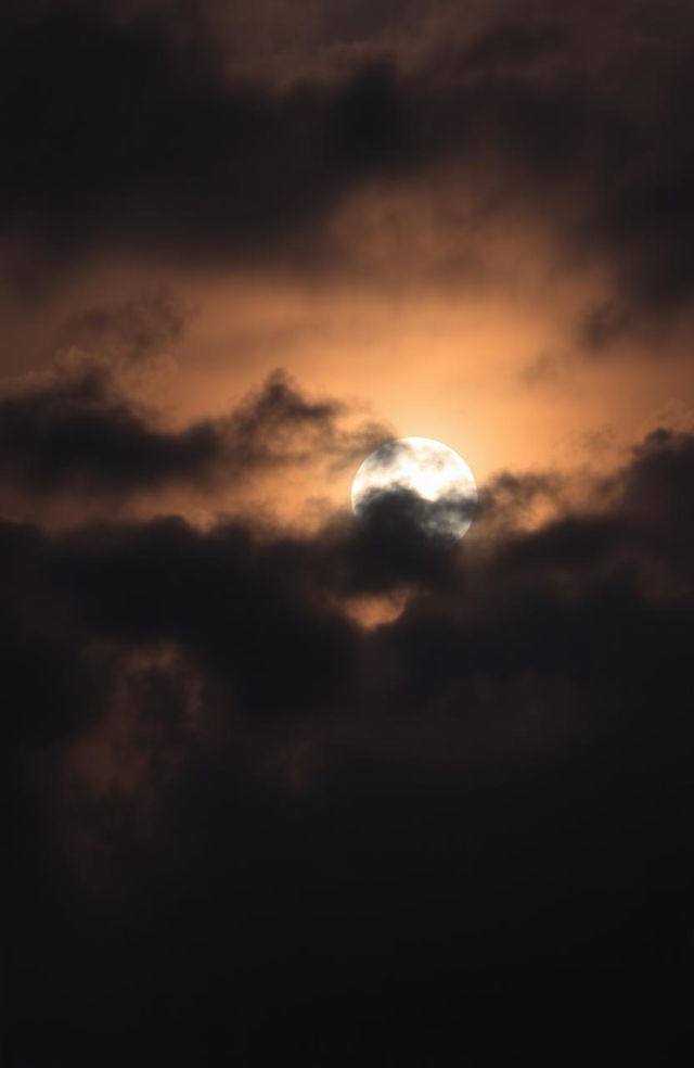 A dramatic sunset sky filled with dark, gloomy clouds, casting an ominous shadow over the horizon