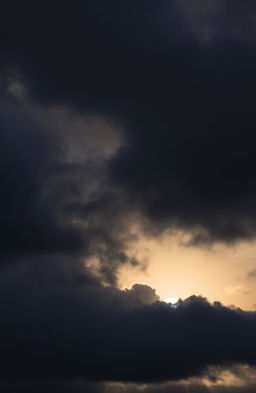 A dramatic sunset sky filled with dark, gloomy clouds, casting an ominous shadow over the horizon