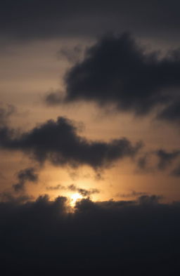 A dramatic sunset sky filled with dark, gloomy clouds, casting an ominous shadow over the horizon