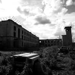 A desolate prison building set in a post-apocalyptic landscape, captured in striking black and white