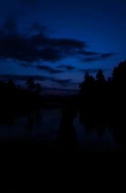 A serene lake at dusk, with a dark, mysterious atmosphere