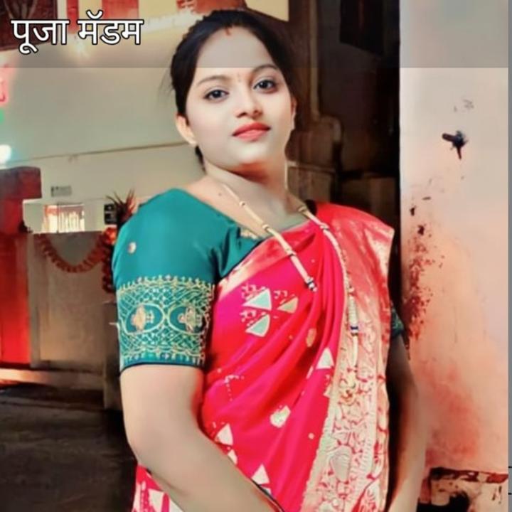 A beautiful woman wearing a vibrant red and green traditional saree, standing confidently in an outdoor setting