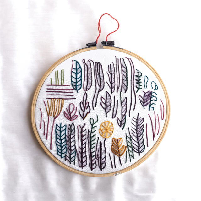 A high-definition image featuring a different embroidery hoop with simple, vibrant designs on a white fabric against a plain white background