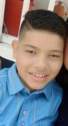 A young boy smiling cheerfully while wearing a sporty blue shirt with a button-up design