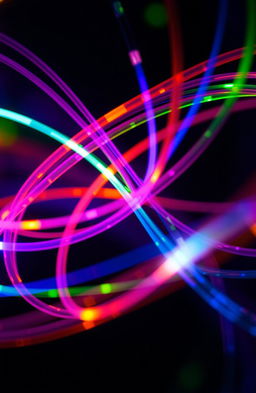 A close-up view of vibrant fiber optic cables, glowing with a spectrum of colors, swirling together in dynamic patterns