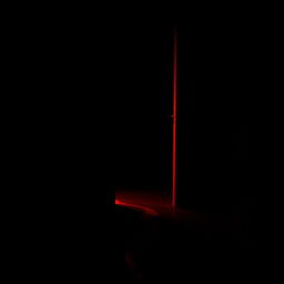 A black dark room featuring a slightly open door, with a vivid red light streaming out from the gap