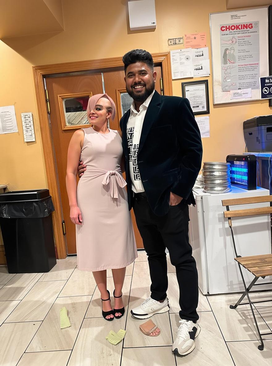 A stylish couple posing happily in a restaurant, showcasing traditional and contemporary fashion