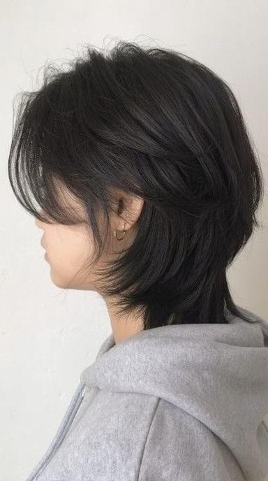 A young adult with long, flowing black hair styled in a layered, textured cut, showcasing vibrant shine